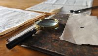 Newspaper, book and magnifying glass on the table